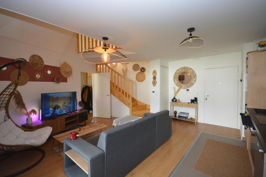 a living room with a couch and a television at Appartement Duplex équipé 12 mn saint Lazare et 15mn stade de France in Colombes
