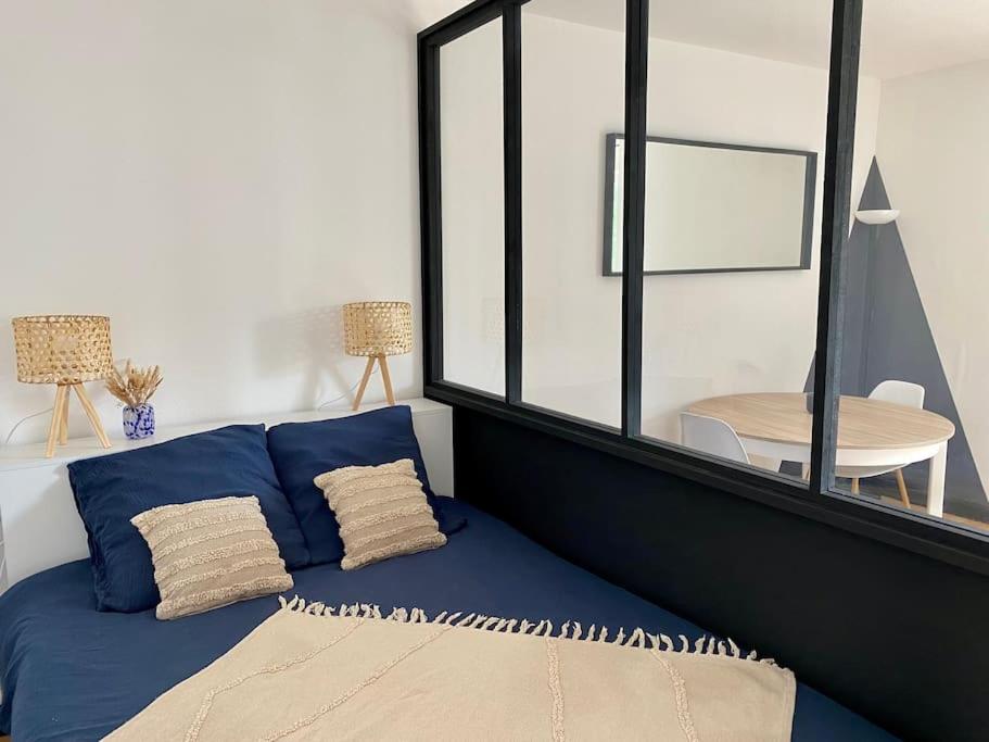 - un lit bleu dans une chambre avec une grande fenêtre dans l'établissement Studio près de la mer avec vélos, à Concarneau