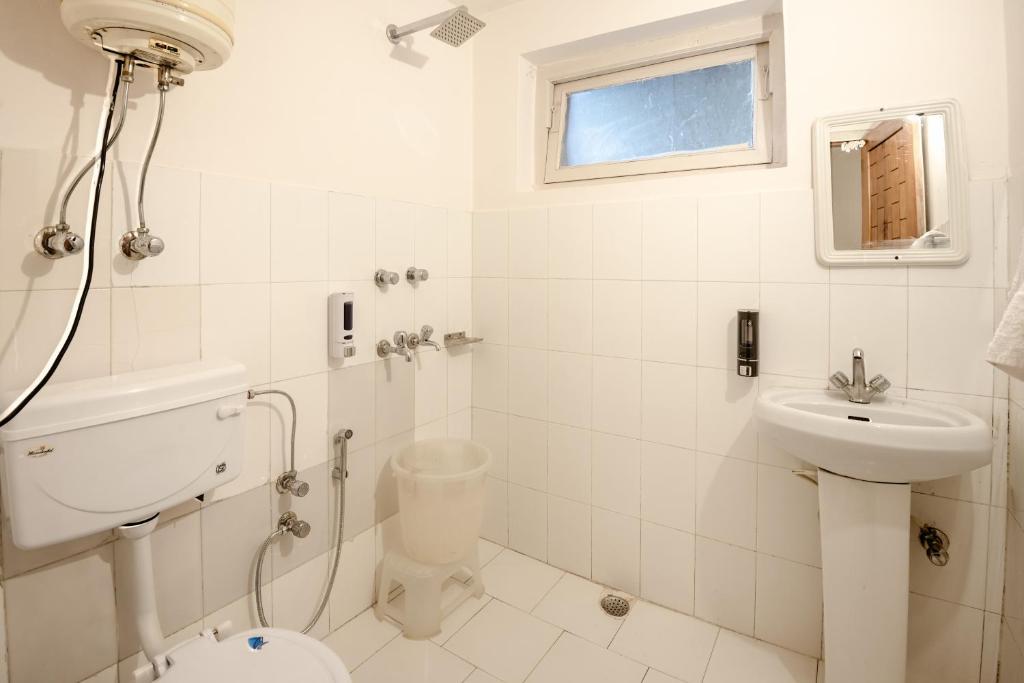 a white bathroom with a toilet and a sink at Drifters Inn - The Hidden Tribe in Manāli