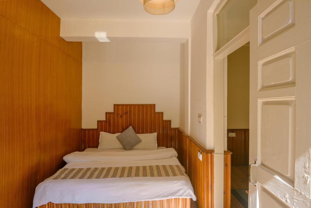 a bedroom with a bed with a wooden headboard at Drifters Inn - The Hidden Tribe in Manāli