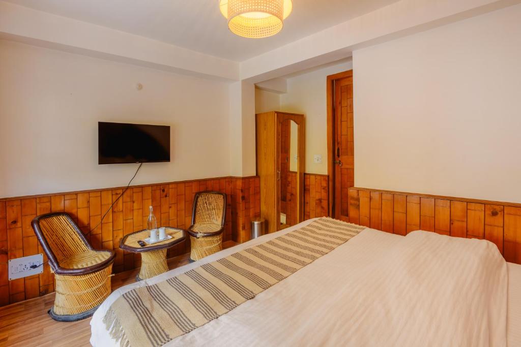 a bedroom with a bed and a table and chairs at Drifters Inn - The Hidden Tribe in Manāli