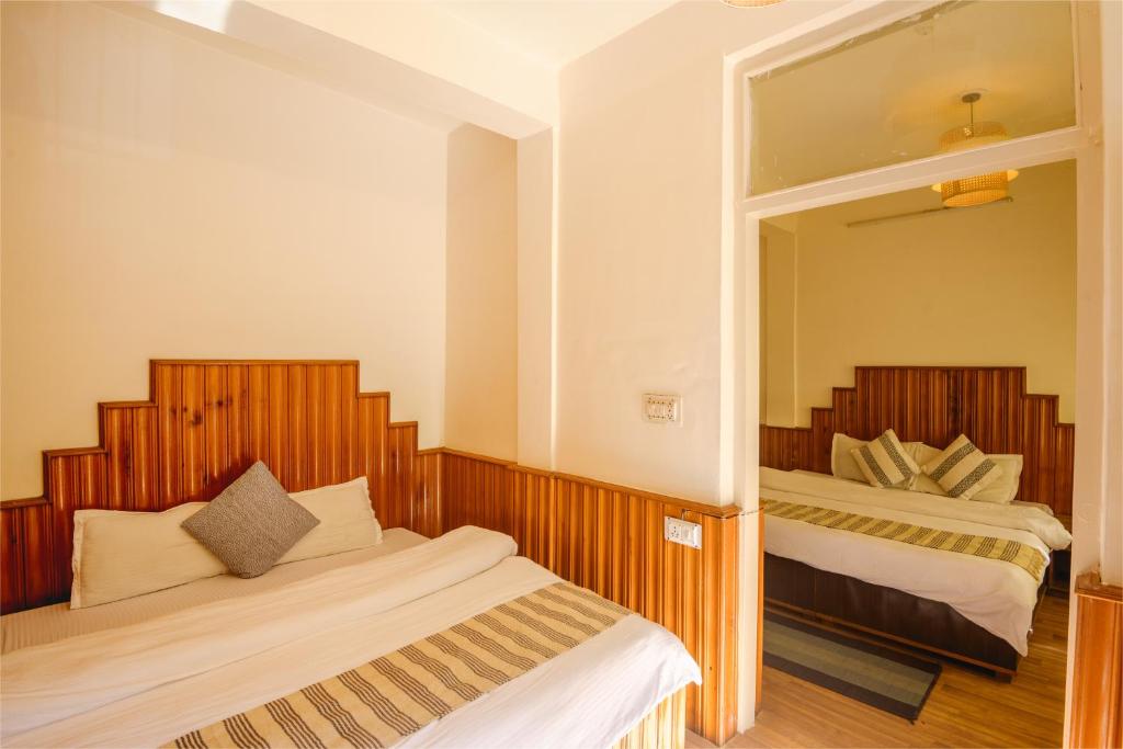 a bedroom with two beds and a mirror at Drifters Inn - The Hidden Tribe in Manāli