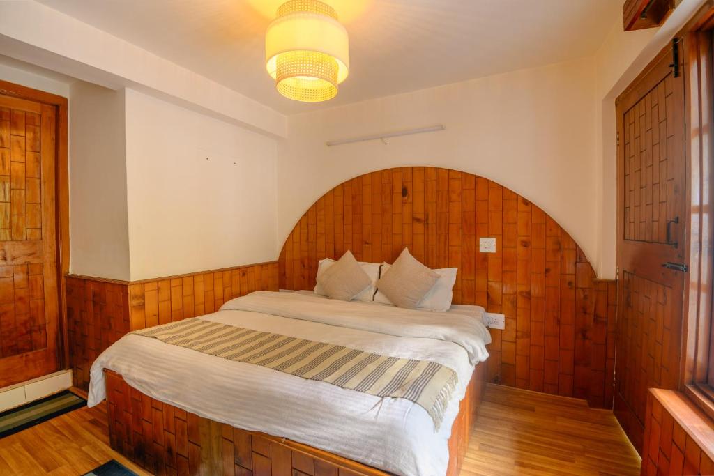 a bedroom with a large bed with a wooden headboard at Drifters Inn - The Hidden Tribe in Manāli