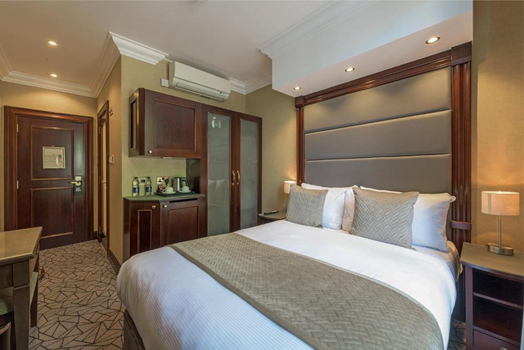 een hotelkamer met een groot bed en een bureau bij Hyde Park International in Londen