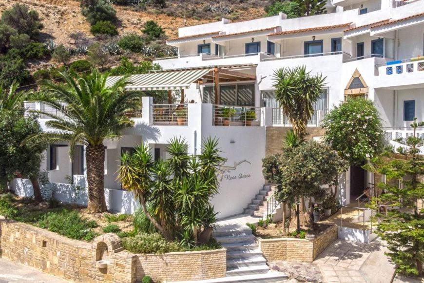 a white building with palm trees in front of it at Neos Ikaros in Agia Galini