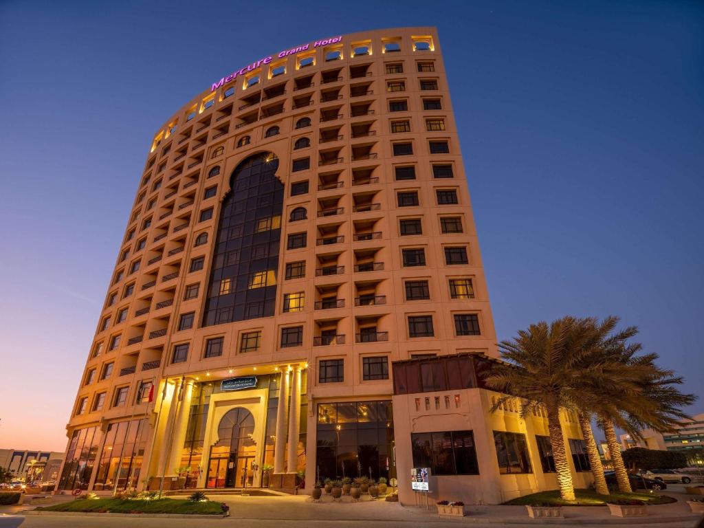 wysoki budynek z znakiem na górze w obiekcie Mercure Grand Hotel Seef - All Suites w mieście Manama