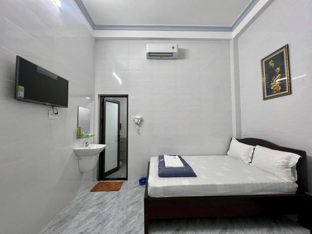 Dormitorio pequeño con cama y lavamanos en Nhà Nghỉ Thiên Tân 2 en Quang Ngai