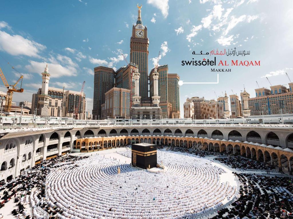 una gran multitud de personas bajo un puente con una torre de reloj en Swissotel Al Maqam Makkah, en La Meca