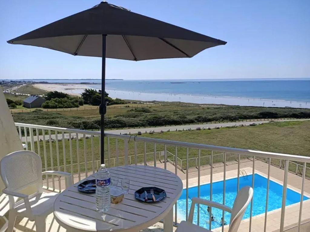 - une table avec un parasol sur un balcon à côté de la piscine dans l'établissement Appartement d'une chambre a Guidel a 100 m de la plage avec vue sur la mer piscine partagee et balcon amenage, à Guidel