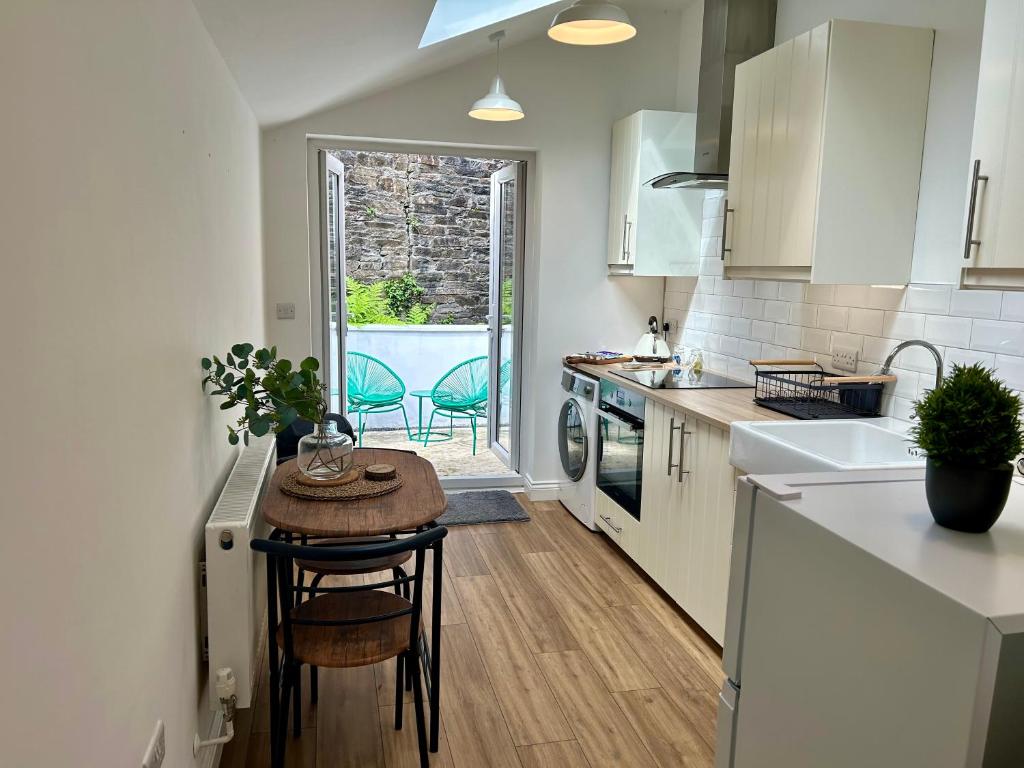 uma cozinha com uma pequena mesa e um lavatório em The Cottage, Bridge House em Laxey