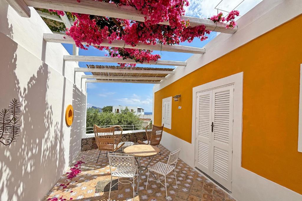 een patio met een tafel, stoelen en bloemen bij Casa Corallo in Panarea