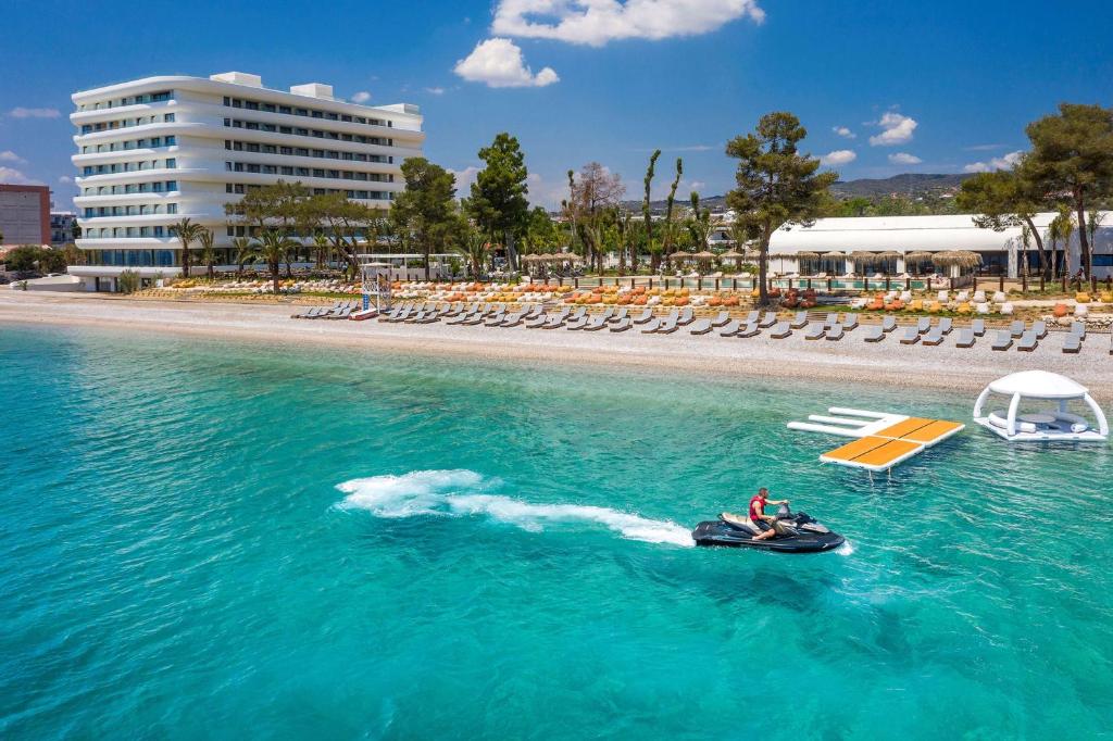 a person on a jet ski in the water near a beach at Isla Brown Corinthia Resort & Spa, Curio Collection by Hilton in Agioi Theodoroi