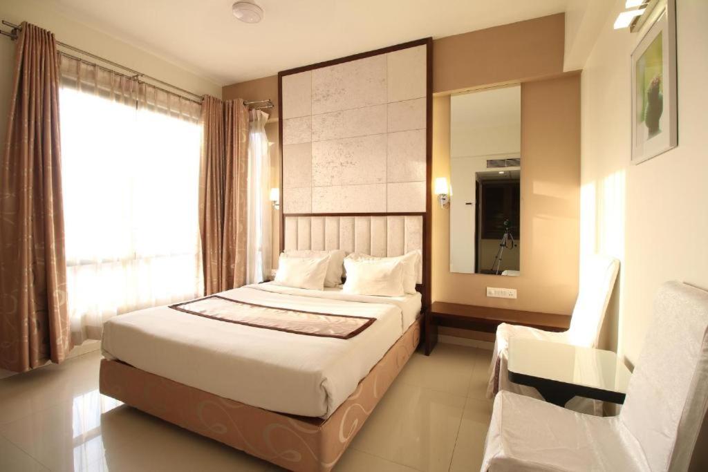 ein Schlafzimmer mit einem Bett, einem Stuhl und einem Fenster in der Unterkunft Hotel Silver Inn Executive , Aurangabad in Aurangabad