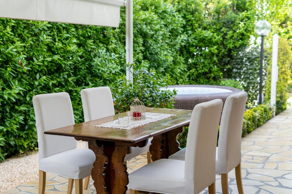 drewniany stół z białymi krzesłami i wanną w obiekcie Villino Claudia w mieście Forte dei Marmi