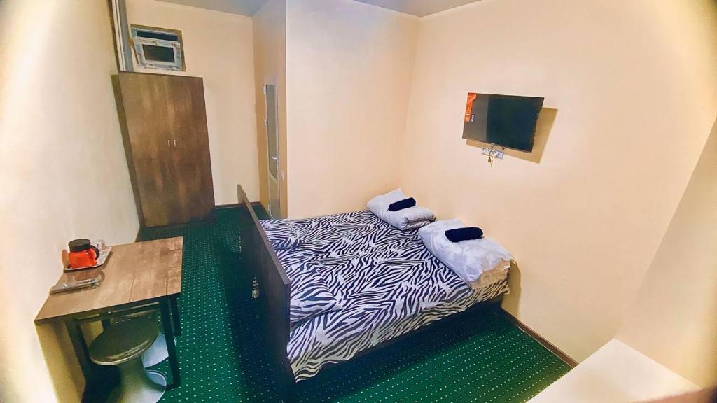 Habitación pequeña con cama con estampado de cebra y escritorio. en Registan Family Hotel, en Samarkand