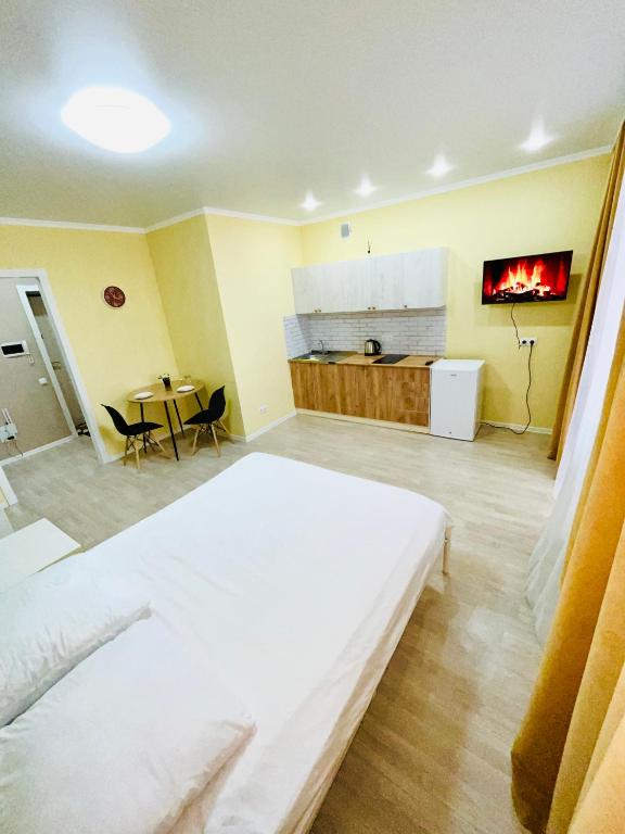 um quarto com uma cama branca e uma cozinha em 1-комнатная комфортная кухня-студия со всеми удобствами em Qostanay