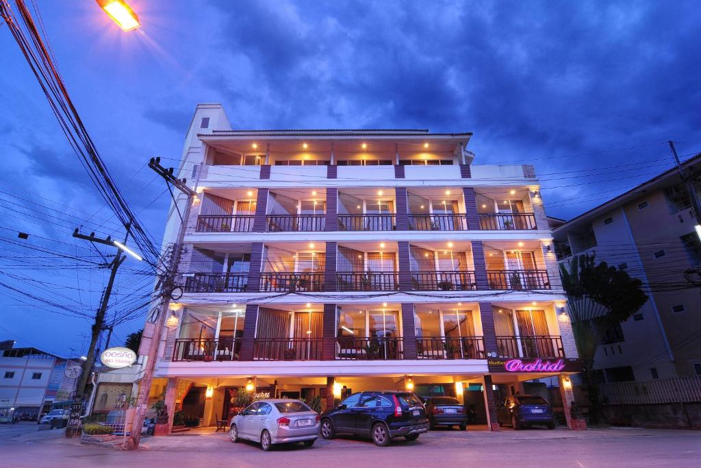 un edificio blanco con coches estacionados frente a él en Khon Kaen Orchid Hotel en Khon Kaen