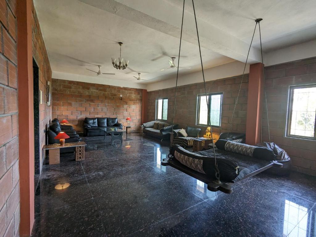a living room with black couches and a brick wall at Spacious farmhouse in Vikārābād