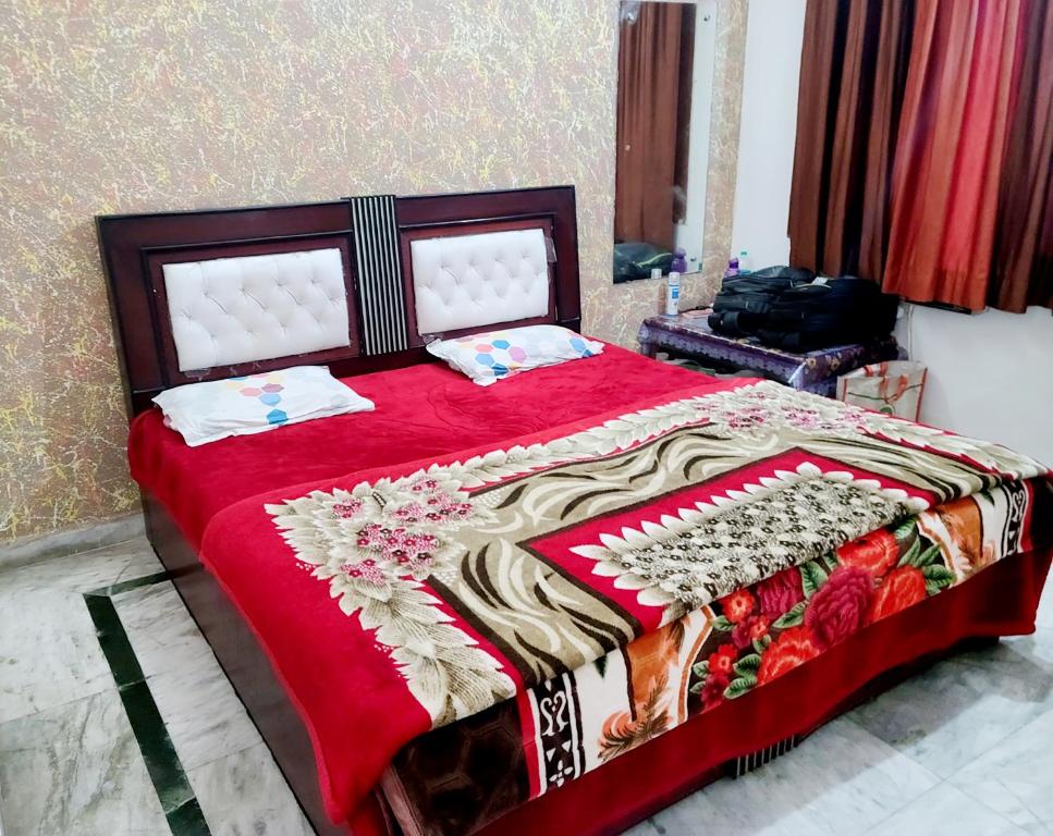 um quarto com uma cama vermelha e um cobertor vermelho em Hotel Hari Krishnashrya em Vrindavan