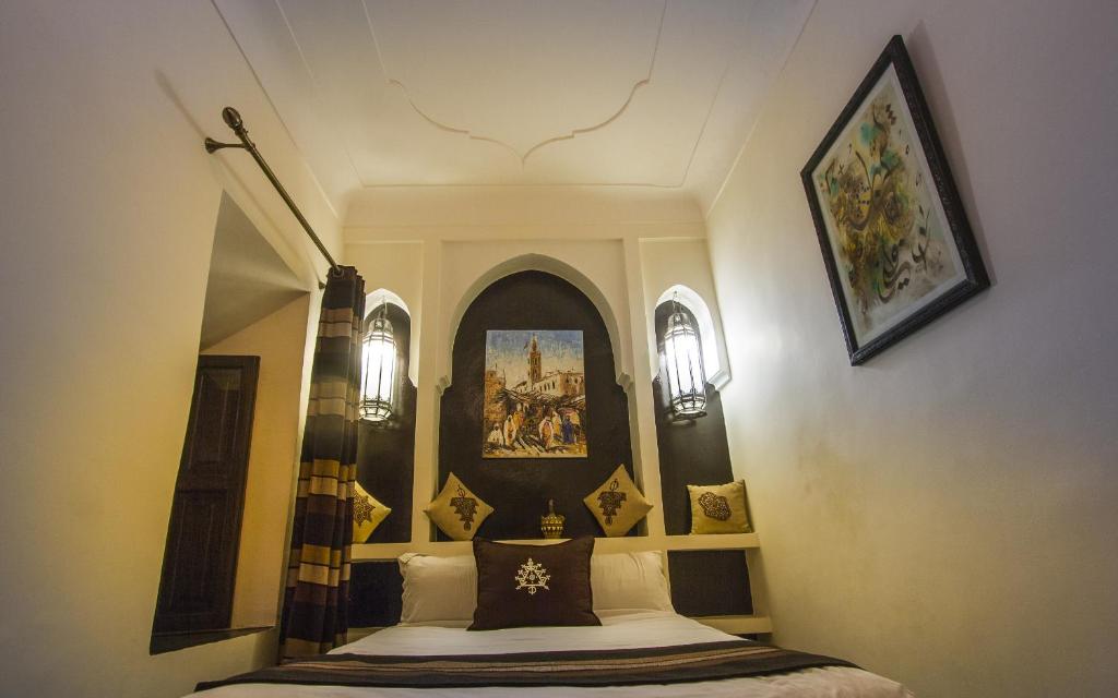 1 dormitorio con 1 cama con una pintura en la pared en Riad Maud, en Marrakech