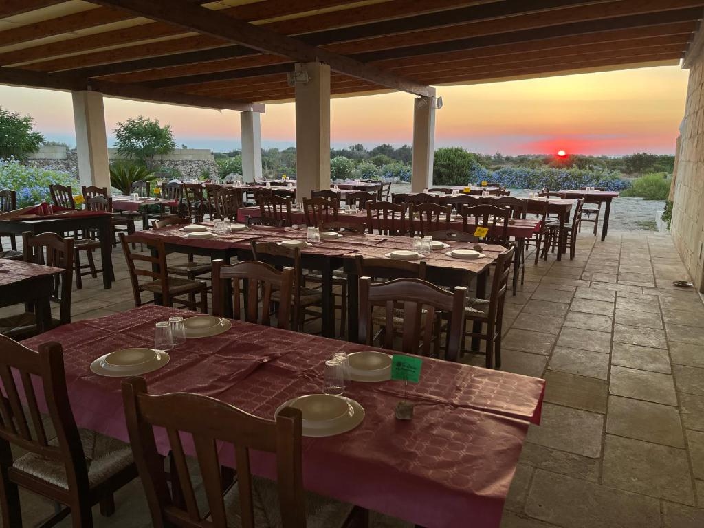 un ristorante con tavoli e sedie con il tramonto sullo sfondo di Agriturismo La Lucia a Sant'Isidoro