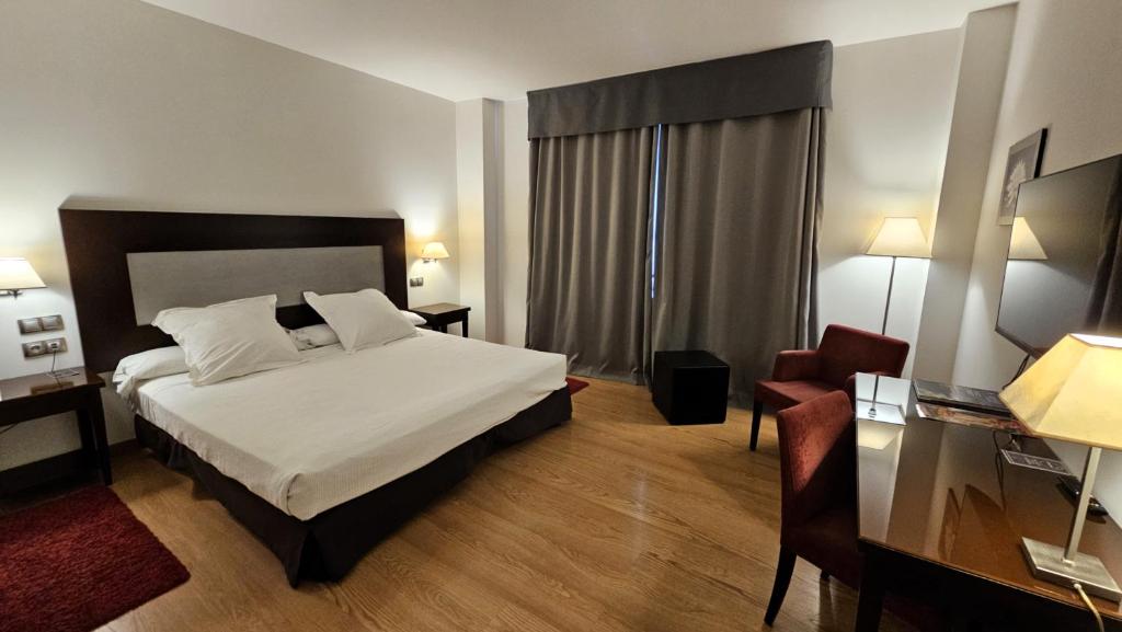 巴達霍斯的住宿－博維達斯酒店，一间卧室配有一张床、一张桌子和一把椅子