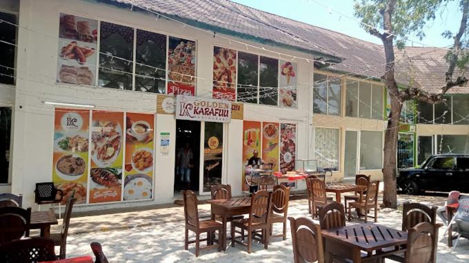 a restaurant with tables and chairs in front of a building at Harmony Homes Beachfront in Diani Beach