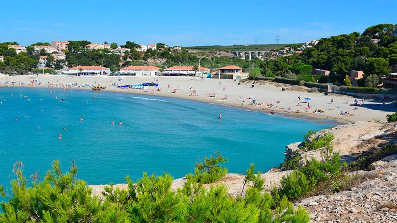 une plage avec un groupe de personnes dans l'eau dans l'établissement appartement bord de mer Martigues, à Martigues