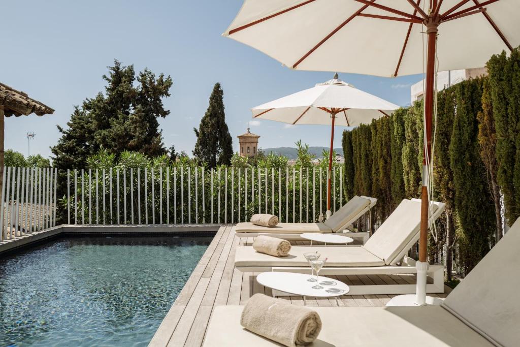 una piscina con 2 sillas y una sombrilla en Convent de la Missio - Grand Luxury Boutique hotel, Adults Only en Palma de Mallorca