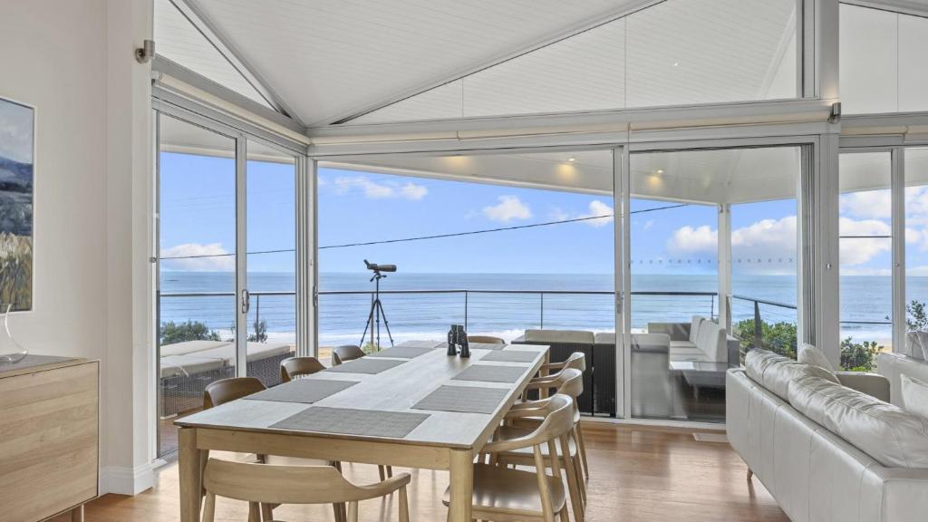 a dining room with a table and a view of the ocean at 'A Beachside Getaway - 8' by HolidayCo in Killcare