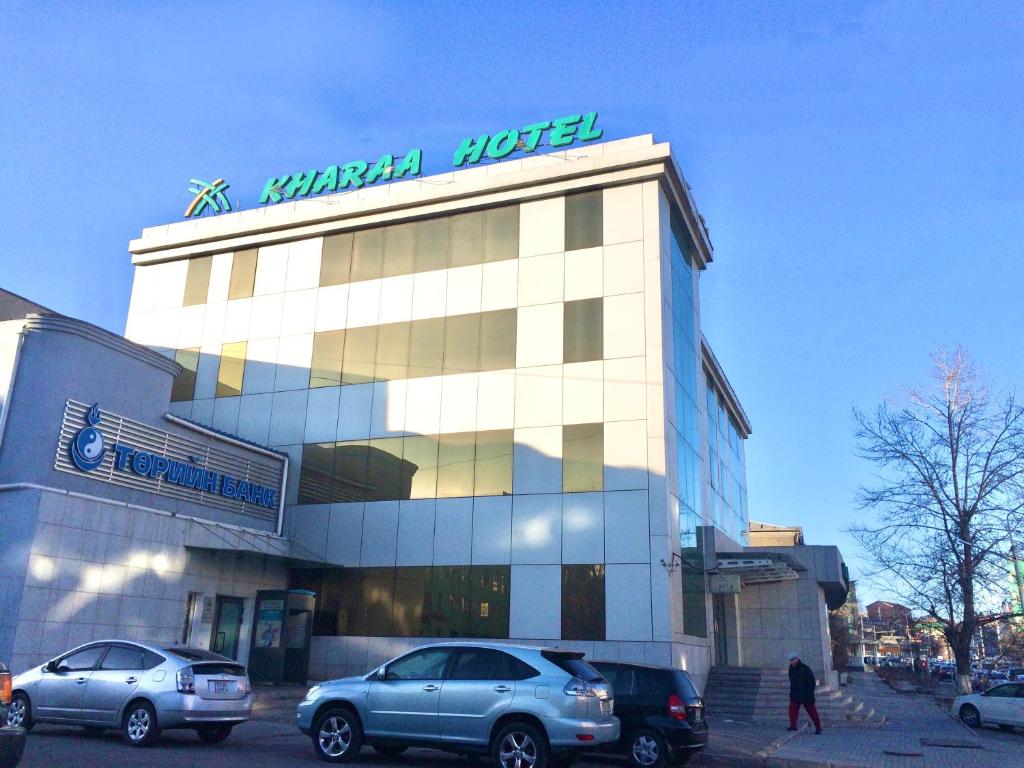 un edificio con dos coches estacionados frente a él en Kharaa Hotel & Restaurant, en Ulán Bator