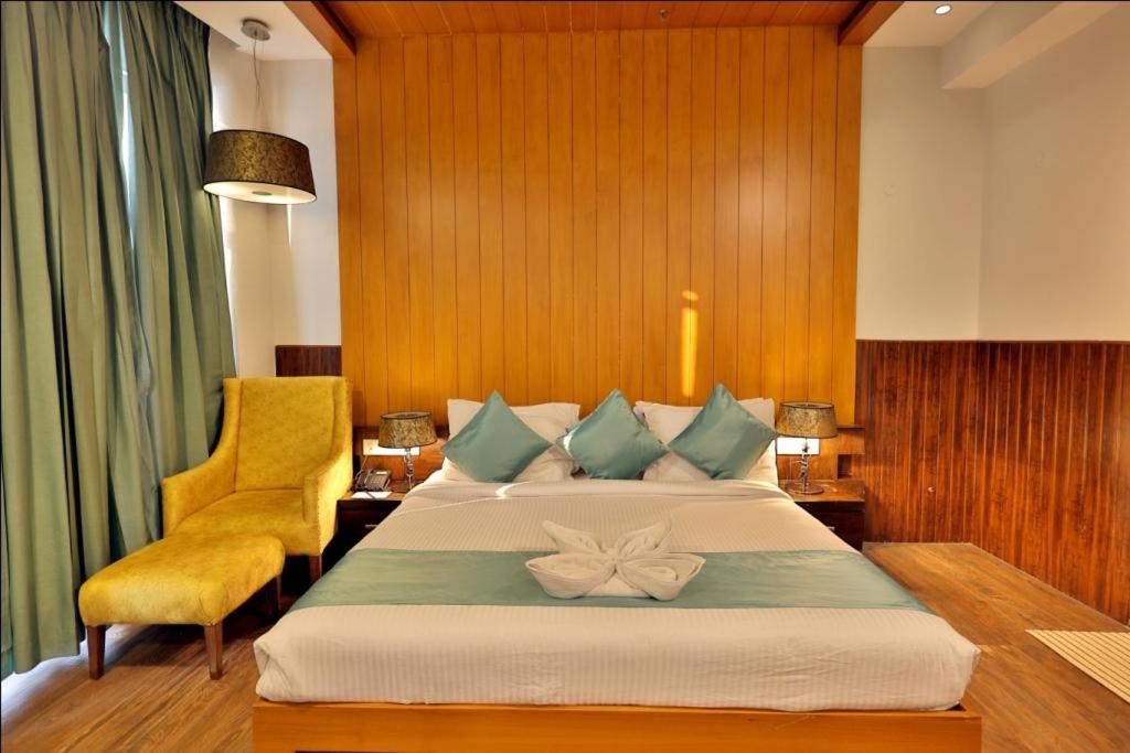 a bedroom with a large bed and a yellow chair at Hotel The Amaris in Rishīkesh