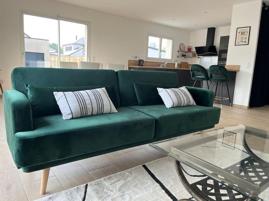 un canapé vert dans un salon avec une table dans l'établissement La Maison des Copains au coeur du DDAY, à Carentan