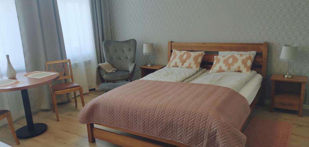 - une chambre avec un grand lit et une chaise dans l'établissement Apartamenty Po Kominiarzach I, à Chełmno
