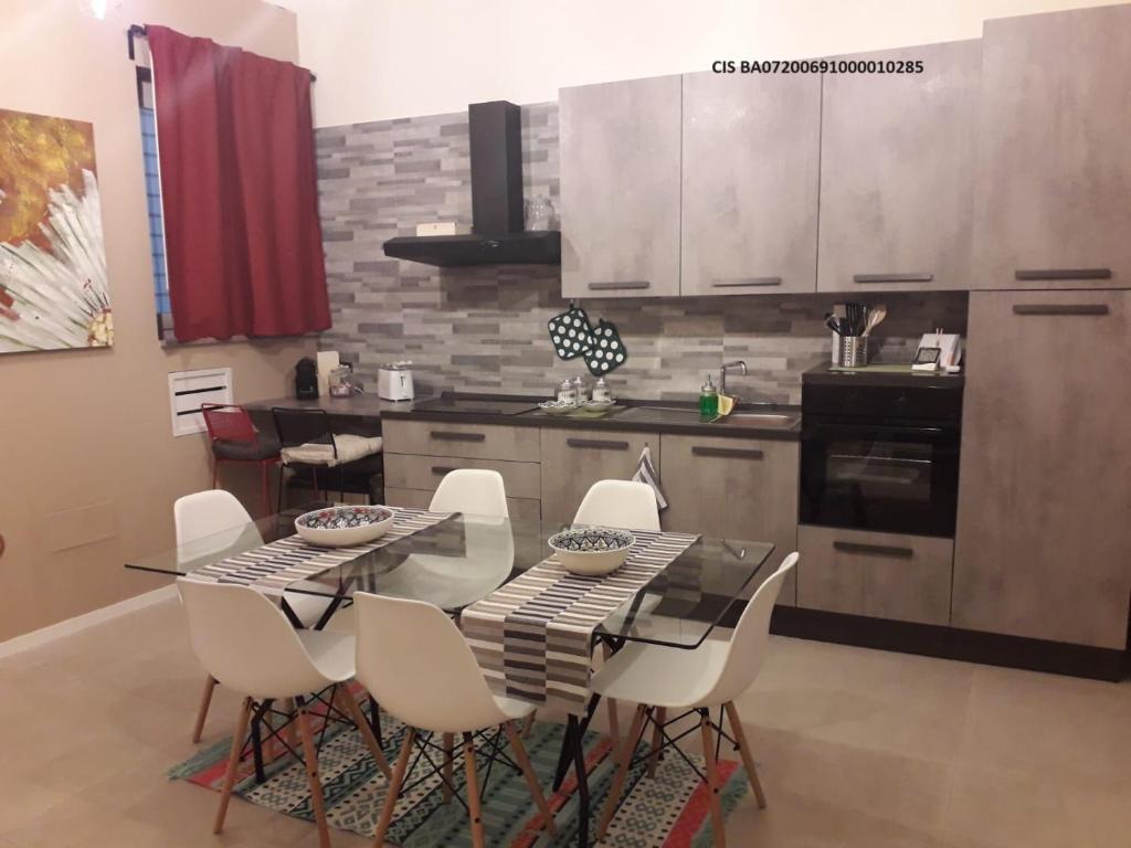 cocina con mesa de comedor y sillas blancas en Nuovissimo appartamento lungomare (check out 13:00), en Bari