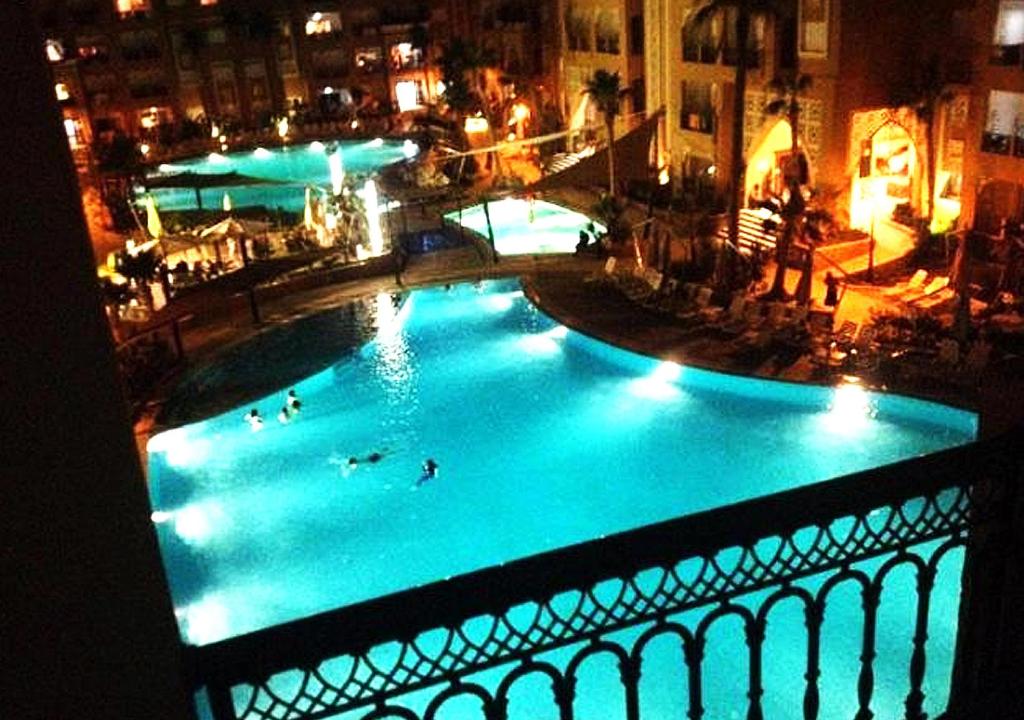 a large pool with people swimming in it at night at appart très luxueux 6 personnes in El Ahmar