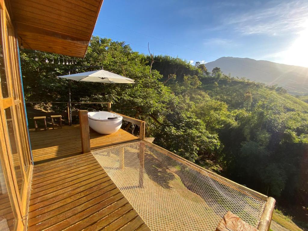 a deck with an umbrella and a bath tub on it at Pousada Sitio Barreirinha in Engenheiro Passos