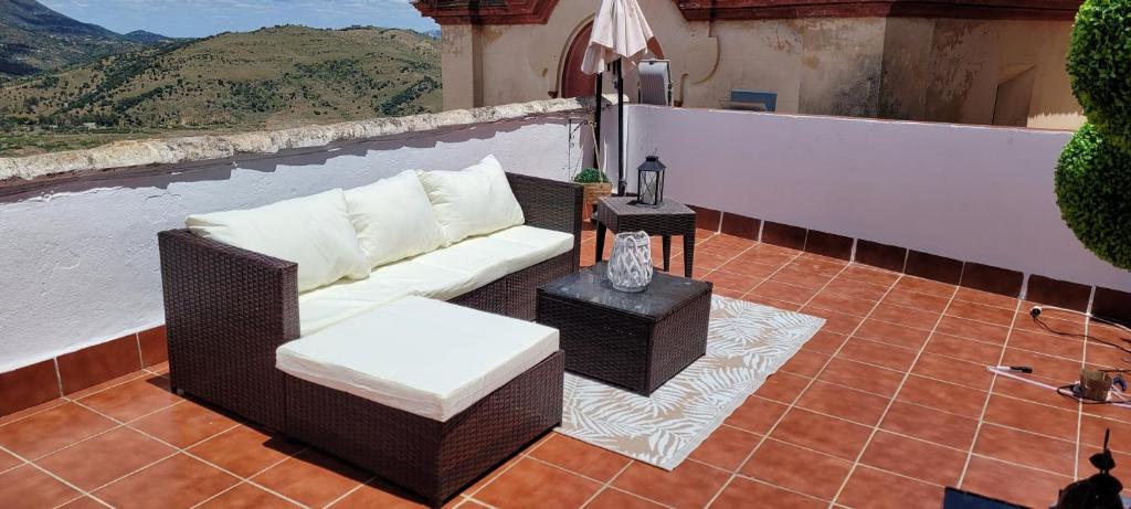 a wicker couch and a table on a balcony at Apartamentos Mirador en la Plaza de Zahara in Zahara de la Sierra