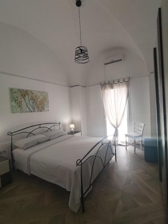 a white bedroom with a bed and a window at A Casa di Simo in Leverano