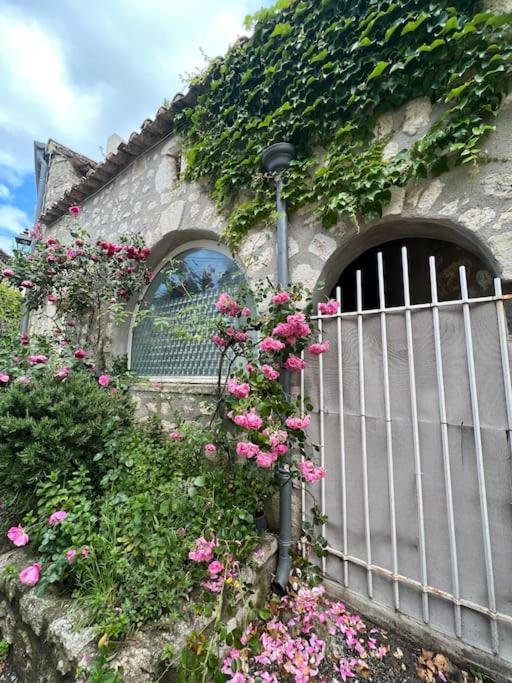 une clôture avec des fleurs roses devant un bâtiment dans l'établissement Appartement au cœur de La Garde Adhémar, à La Garde-Adhémar
