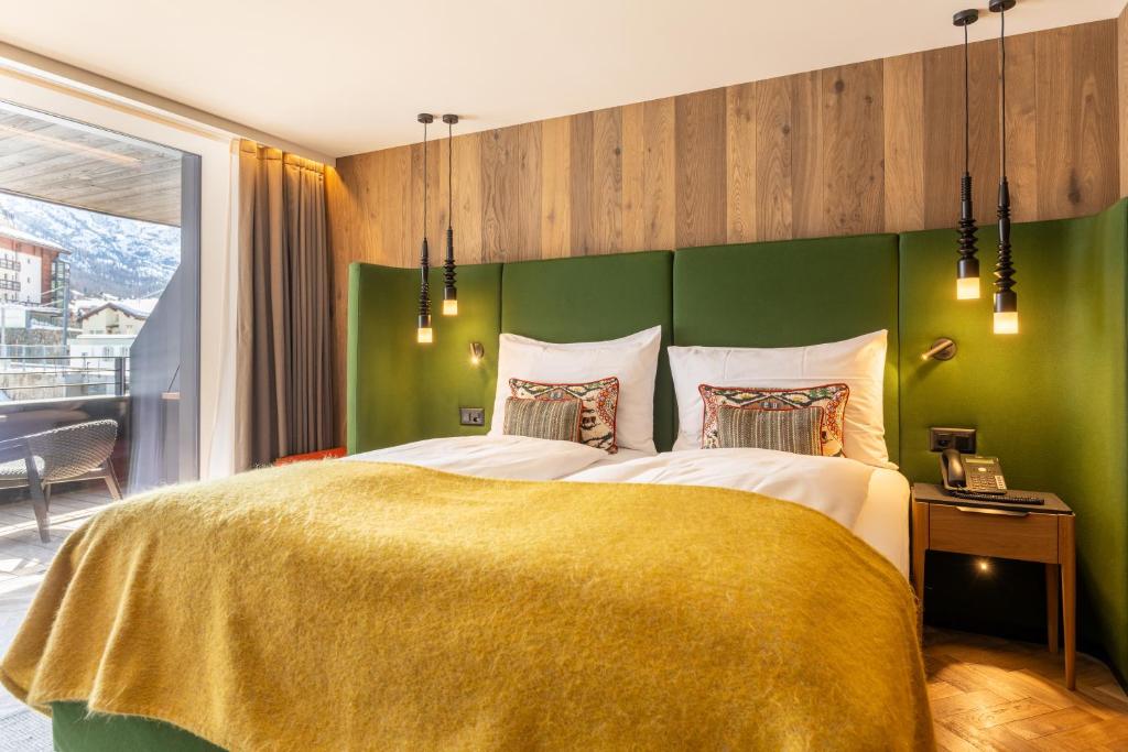 a bedroom with a large bed with a green wall at Hotel ZERMAMA Zermatt in Zermatt
