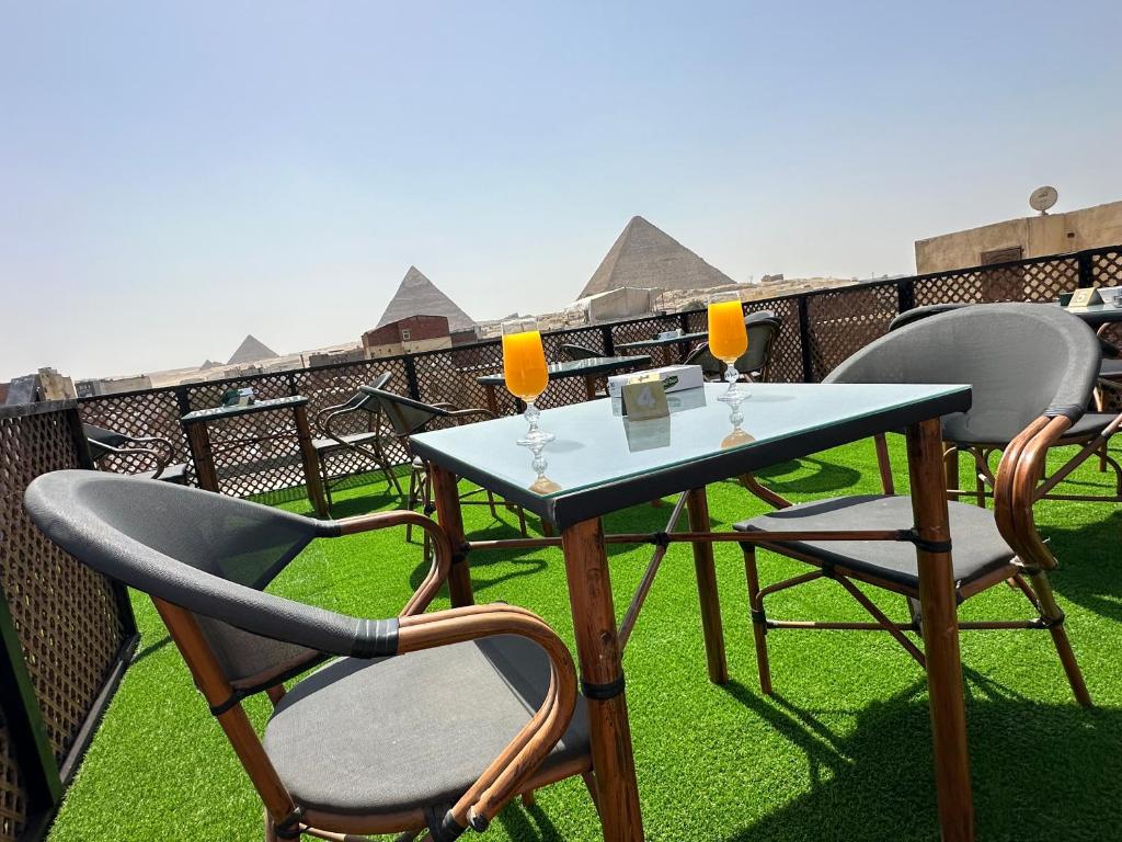 una mesa con 2 sillas y 2 vasos en el balcón en Nefertari pyramids inn, en El Cairo