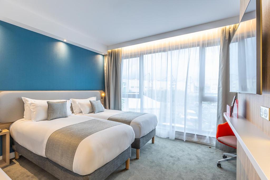 a hotel room with two beds and a large window at Holiday Inn Express Ajaccio by IHG in Ajaccio