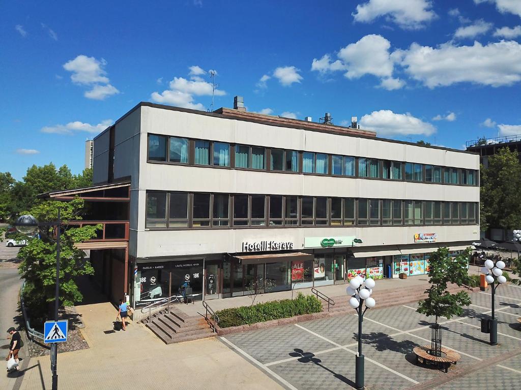 um grande edifício branco com pessoas andando em frente dele em Hotelli Kerava em Kerava