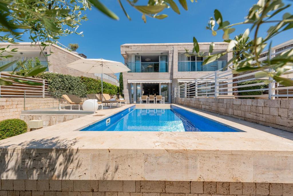 a swimming pool in front of a house at Villa Camelia ZadarVillas in Petrcane