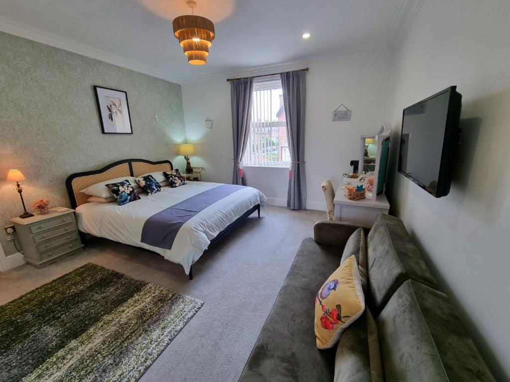 um quarto com uma cama grande e um sofá em The Snug Lytham em Lytham St Annes