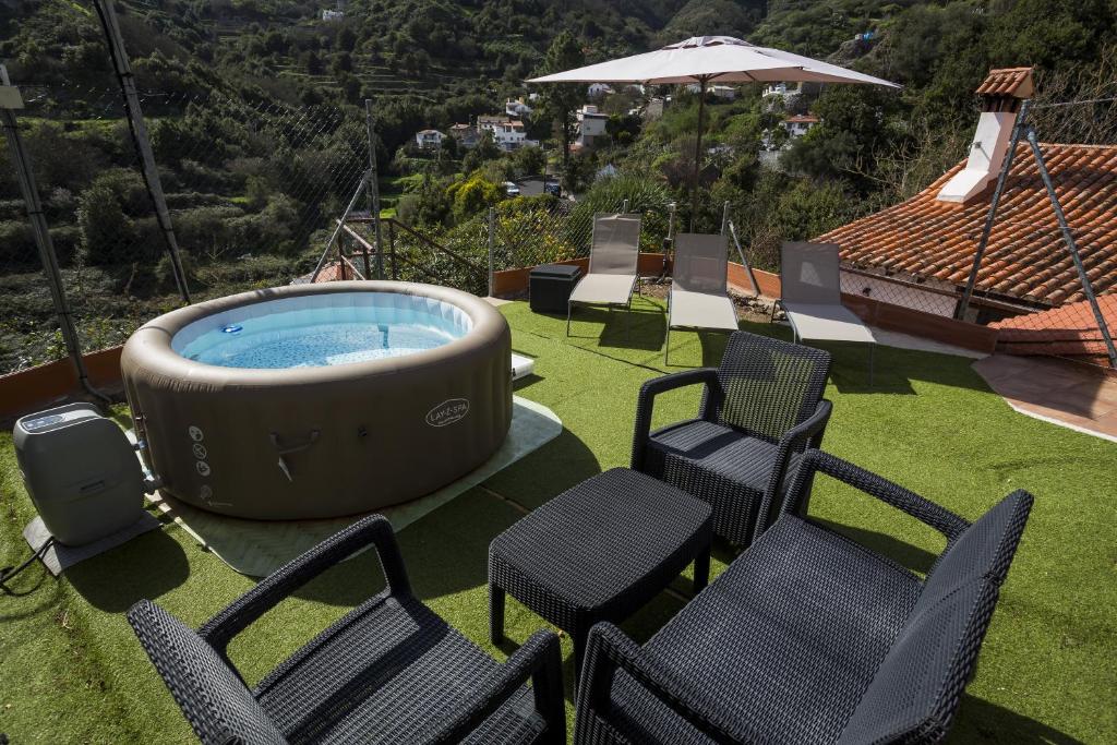 a group of chairs and a hot tub on a lawn at Casa Rural La Escalerilla in Teror