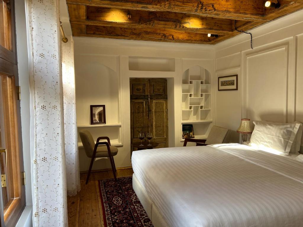 a bedroom with a white bed and a wooden ceiling at Usman Heritage Hotel in Bukhara