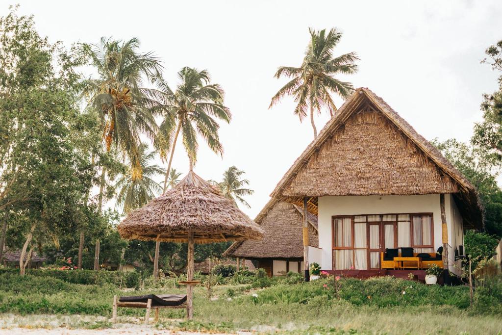 a house with palm trees and a bench in front of it at Maisara Mafia Beach Lodge in Kilindoni
