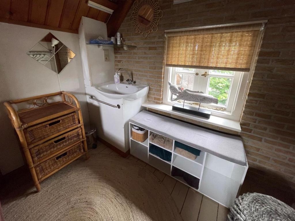 Una pequeña cocina con fregadero y ventana. en Galerie Petit Delfshaven, en Róterdam